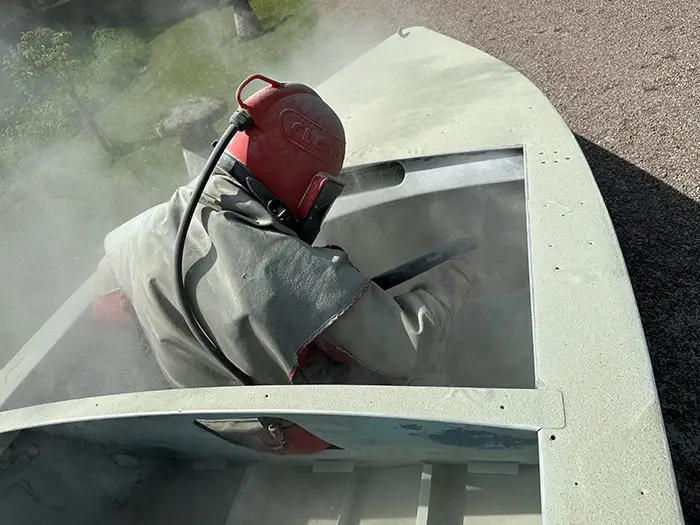 man blasting a metal boat